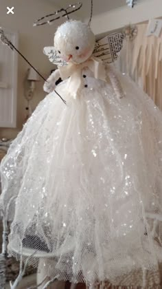 a white teddy bear in a dress hanging from a rack