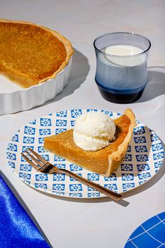 a slice of pie on a plate with ice cream and a glass of milk next to it