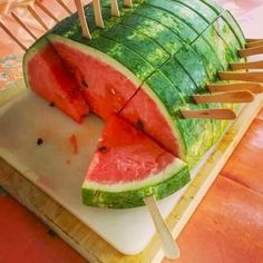 a large piece of watermelon sitting on top of a cutting board with toothpicks sticking out of it