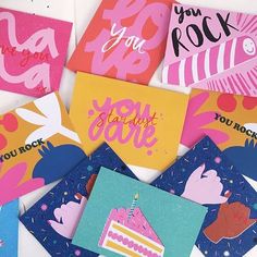 many different greeting cards are arranged on a white surface with pink, blue and yellow colors