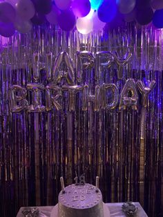 a birthday cake sitting on top of a table in front of balloons and streamers