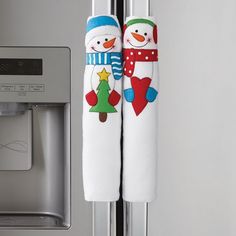 two snowmen are hanging from the handle of a refrigerator