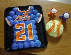 a birthday cake with an orange and blue football jersey on it next to cupcakes