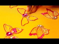 someone is working on some gold and red decorations with beads in the shape of flowers