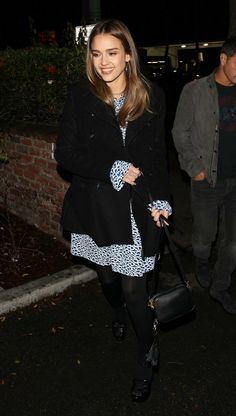 a woman walking down the street carrying a black bag