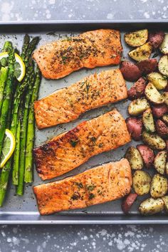 salmon, potatoes and asparagus on a baking sheet with lemon wedges for garnish