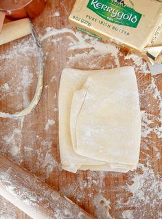 dough and flour on a wooden table next to a rolling pin