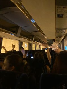 a group of people riding on the back of a bus with their hands in the air