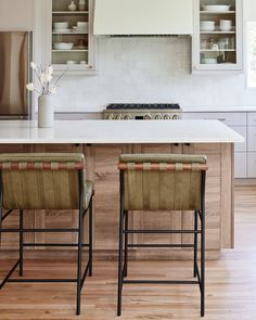 two stools sit in front of an island with built - in stove and oven