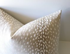 two pillows sitting on top of a white table next to each other, one has a brown and white pattern