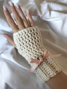 a woman's hand wearing a crochet knitted glove with a bow