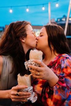 two women kissing each other while eating food