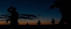 silhouettes of people walking on the beach at sunset