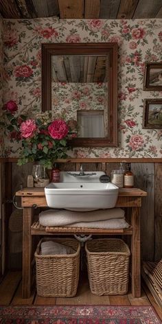 a white sink sitting under a mirror next to a wooden table with flowers on it