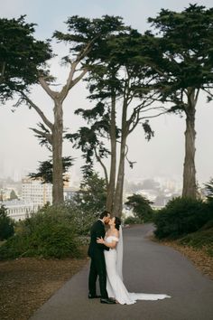 a bride and groom kissing in front of the trees at their san francisco elopement