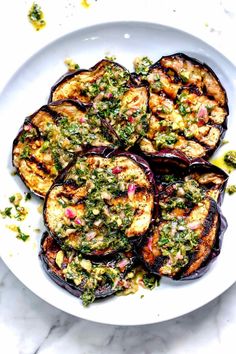 grilled eggplant on a white plate with pesto and parsley sauce