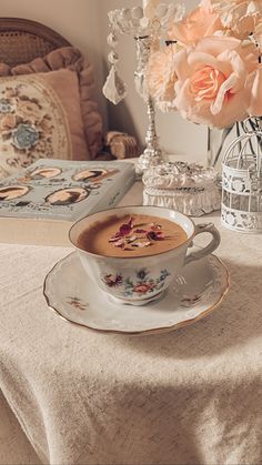 a cup of coffee sitting on top of a saucer next to a vase filled with flowers