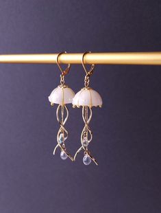 "Introducing our stunning Jellyfish Earrings, crafted with utmost care and fashioned with a unique blend of resin, curved metal charms, and delicate teardrop beads. These enchanting earrings capture the graceful movement of jellyfish in a captivating design that is sure to turn heads. Each intricately detailed jellyfish is meticulously molded from resin, showcasing their ethereal beauty. The curved metal charms add a touch of elegance and whimsy, perfectly complemented by the shimmering teardrop Whimsical Resin Jewelry With Ear Wire, Whimsical White Resin Jewelry, Whimsical Resin Dangle Earrings, White Jelly Fish, Jellyfish Earring, Jellyfish Earrings, Graceful Movement, Bracelet Inspo, Jelly Fish