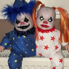 two creepy clown dolls sitting next to each other