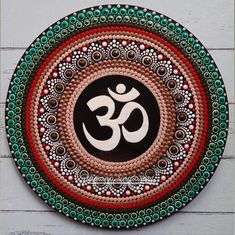 a decorative plate with an omesh symbol painted on the front and side, sitting on a white wooden surface