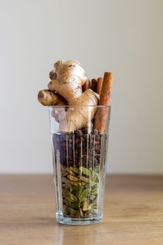 a glass filled with spices and herbs on top of a wooden table