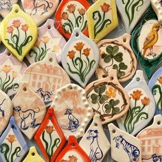 many different shaped ceramic tags with flowers and animals on them, all painted in different colors