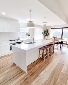 a large kitchen with an island and wooden floors in the center, along with white cabinets