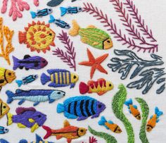 an embroidery pattern with different colored fish and seaweed on white fabric, which has been stitched together