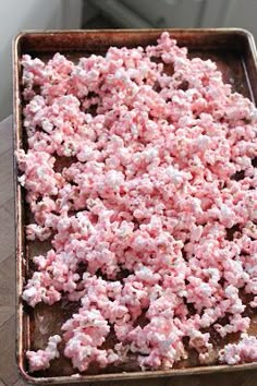 pink and white popcorn is on a baking sheet ready to go into the oven in the oven