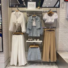 clothes are on display in a store with white brick walls and shelves holding shirts, pants, and shoes