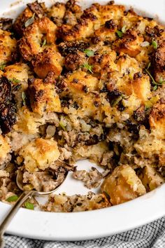 a casserole dish filled with stuffing and topped with a spoon on a checkered cloth