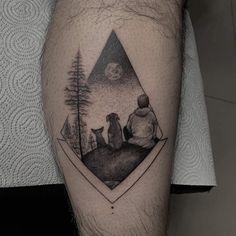 a man's leg with a black and white tattoo on it that has an image of two people sitting in the woods