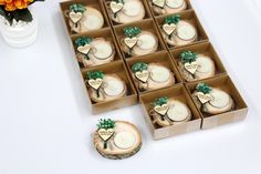 twelve decorated cookies in boxes sitting on a table next to a vase with orange flowers