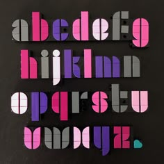 the letters are made up of different colors and shapes, including pink, purple, and grey