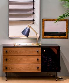 a wooden dresser sitting next to a wall mounted shelf with a lamp on top of it