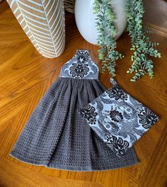 two pieces of crocheted clothing sitting on top of a wooden floor next to a potted plant