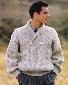 a man wearing a sweater and tie standing in a field