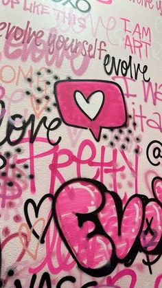 graffiti written on the side of a wall with pink and black writing in different languages