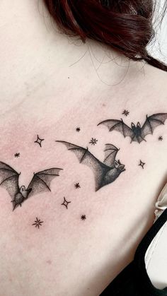 a woman's back with three bats flying in the sky and stars on it