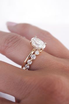 a woman's hand with a diamond ring on top of her finger and an engagement band