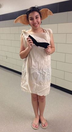 a woman in a white dress holding a black piece of paper and wearing a hat