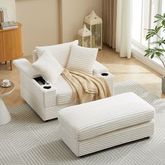 a living room with a white couch and ottoman on the floor in front of a window