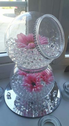 two clear vases with pink flowers in them sitting on a window sill next to plates