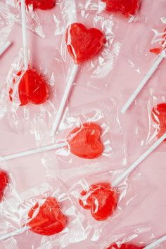 several lollipops are wrapped in plastic on a pink surface