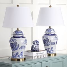 two blue and white vases sitting on top of a table next to a lamp