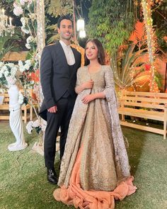 two people standing next to each other in front of a decorated area with flowers and lights