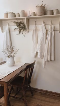 a wooden table topped with a white vase filled with flowers next to a wall mounted shelf