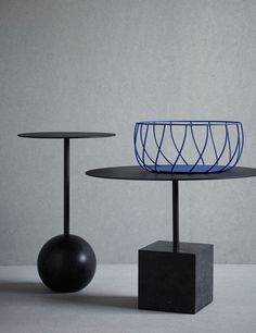 two black tables with metal wire on top and one round table sitting next to each other