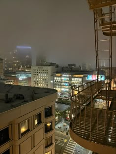 a view of the city at night from a high rise building with fire escape stairs