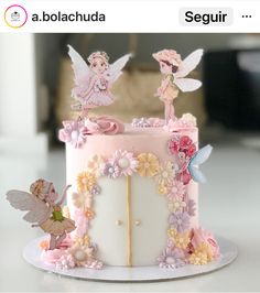 there is a cake decorated with flowers and fairy figurines